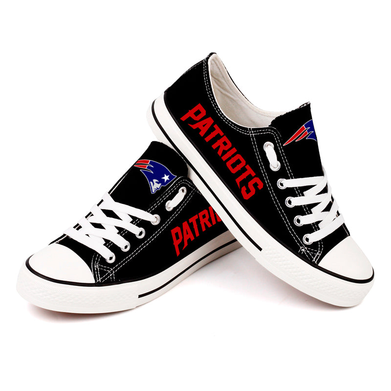 Black New England Patriots canvas shoes crossed over, highlighting the "Flying Elvis" logo and red "PATRIOTS" text. Clean, white laces.