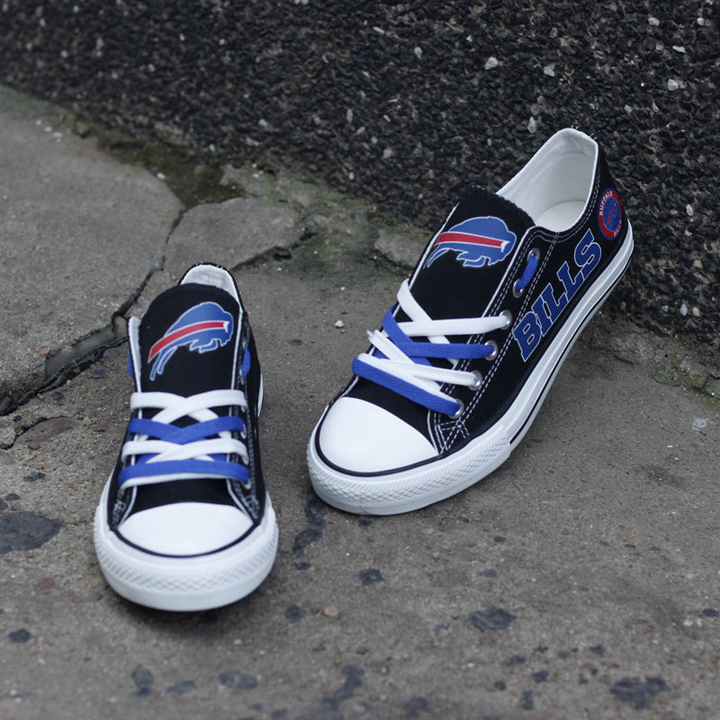 Close-up of black Buffalo Bills canvas shoes on a street background. Focuses on the logo on the tongue and the custom blue laces.