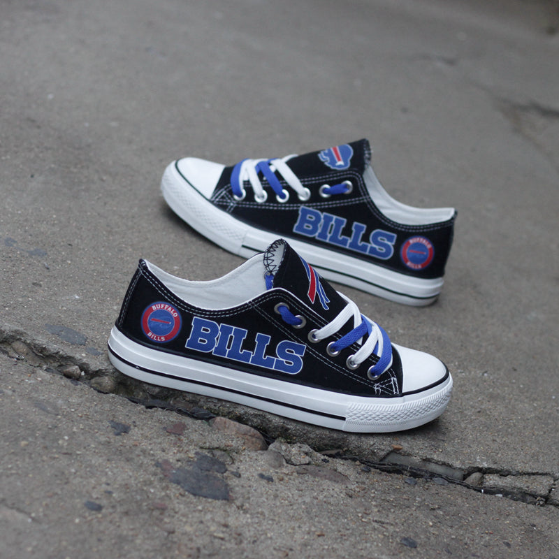 Two black Buffalo Bills canvas low-top shoes on a rough concrete background, showcasing the blue laces and team logo.