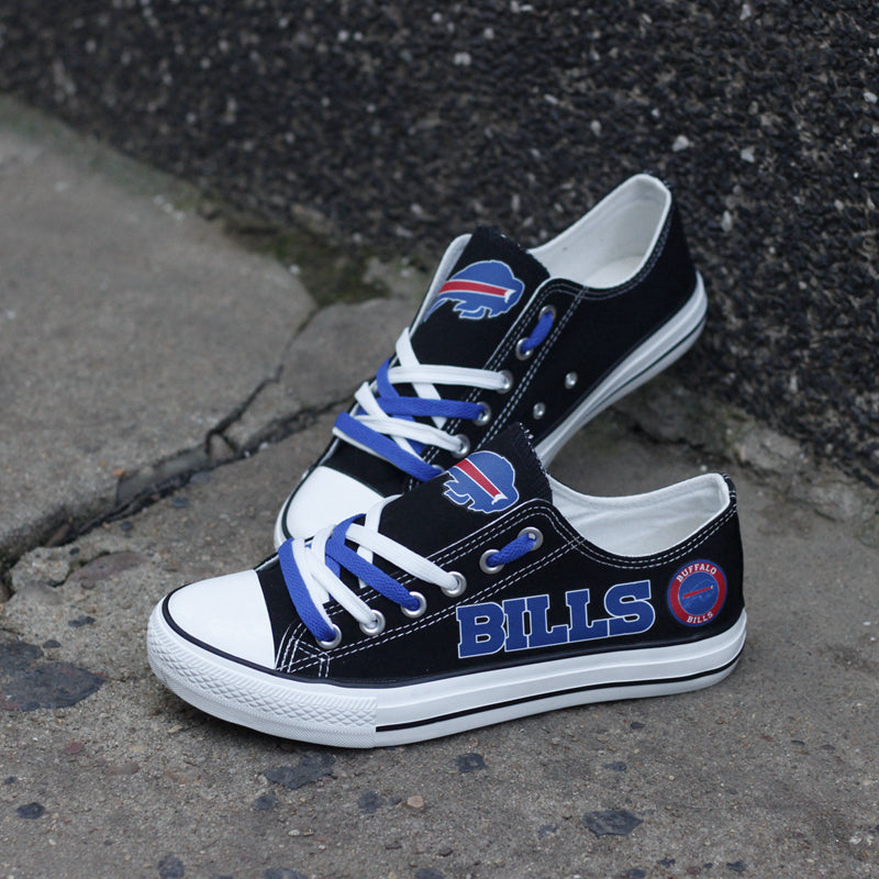Black Buffalo Bills canvas sneakers resting on a concrete surface against a dark wall. Highlights the blue "BILLS" lettering and team logo for an urban look.