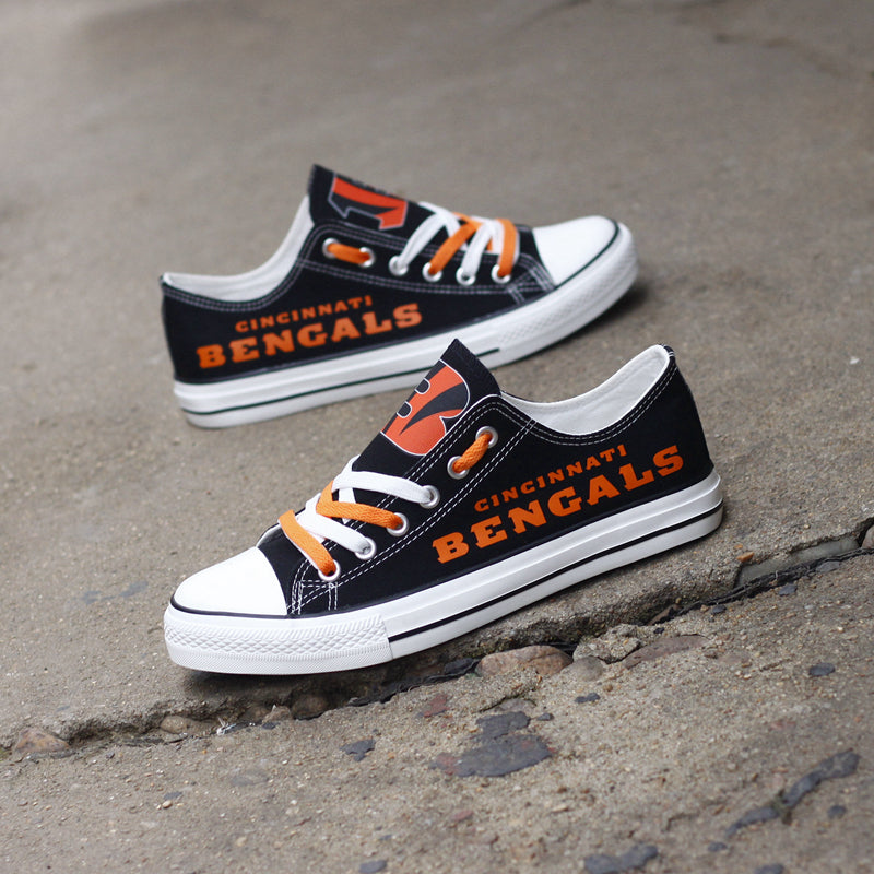 Two black Cincinnati Bengals canvas low-top shoes on a rough concrete background. Showcases the team's orange color and logo for a dynamic outdoor look.