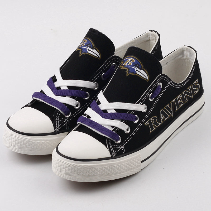 Close-up of black Baltimore Ravens low-top canvas sneakers featuring the Ravens logo and purple laces on a clean white background. Essential NFL supporter shoes.