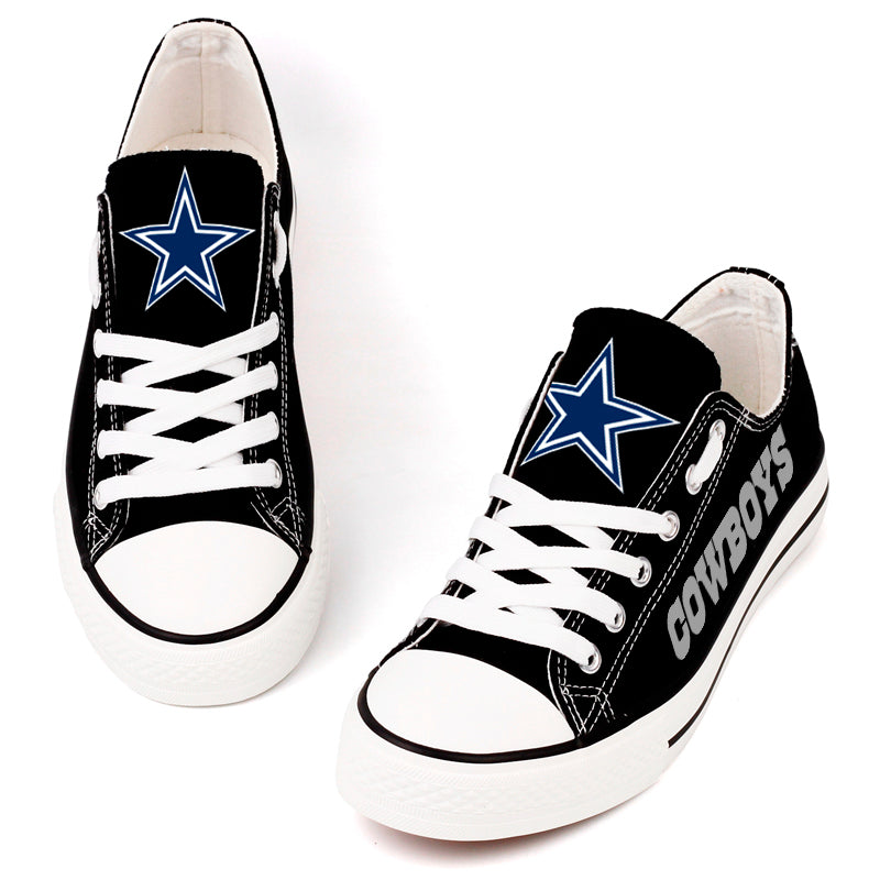 Pair of black Dallas Cowboys low-top canvas shoes with white laces, showing the iconic blue star logo on the tongue and 'COWBOYS' text on the side