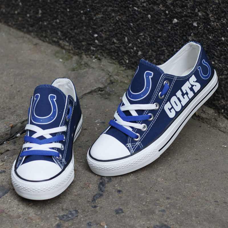 Blue Indianapolis Colts canvas shoes resting on a concrete surface, one standing upright. Features the white horseshoe logo and "COLTS" lettering.