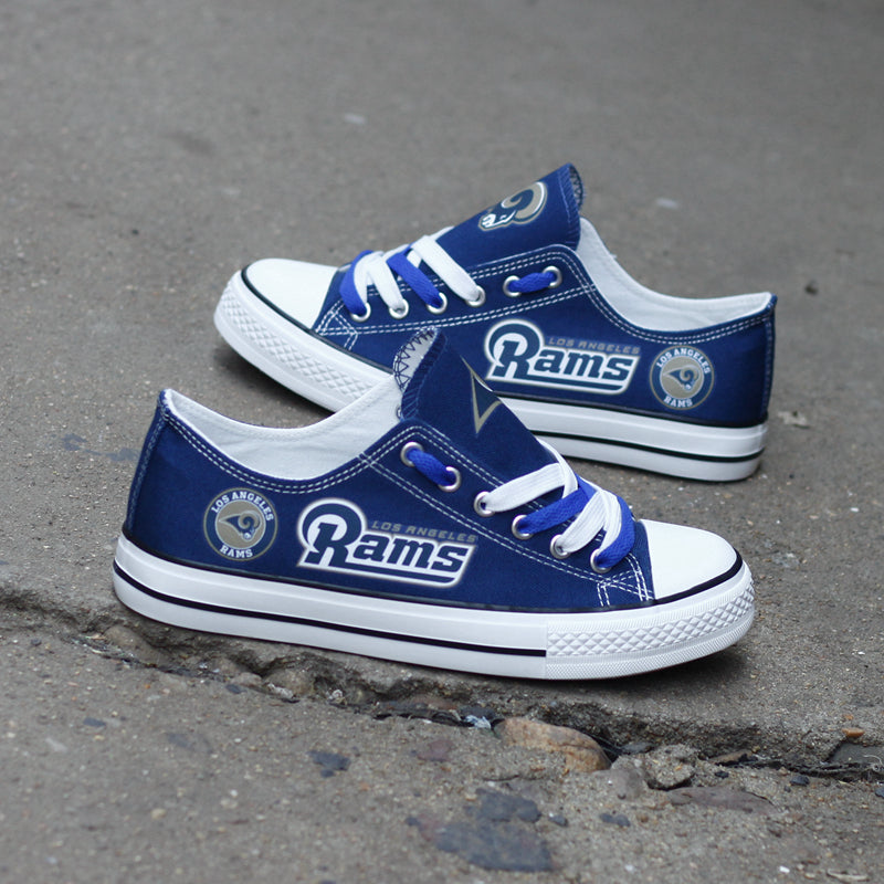 One large and one small royal blue Los Angeles Rams canvas sneaker leaning against a stone wall outdoors. Highlights the gold 'RAMS' lettering and white laces.