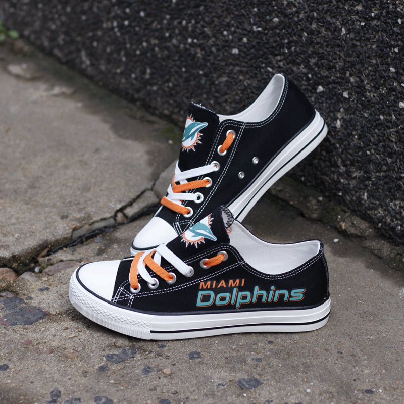 Black Miami Dolphins canvas shoes crossed over, showing the team logo and bold "Dolphins" text. Great gift idea for NFL fans.