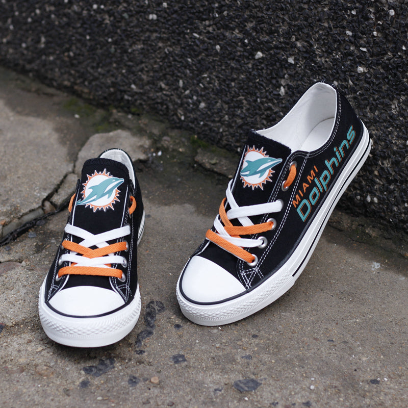 Two black Miami Dolphins low-top shoes on a white background, highlighting the team logo and custom teal and white laces.