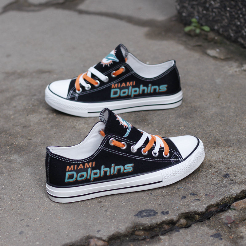 Top-down view of black Miami Dolphins canvas low-top sneakers with white laces. Features the circular Dolphins logo on the tongue. Ideal game day footwear.