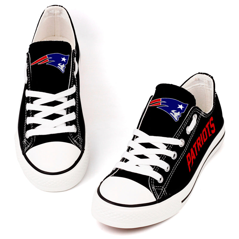 Top-down view of black New England Patriots canvas shoes with white laces. Focuses on the "Flying Elvis" logo on the tongue.