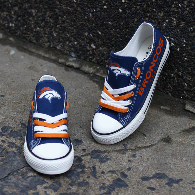 One large and one small navy blue Denver Broncos canvas sneaker on a concrete surface. Shows the orange laces and the iconic horse logo for all ages.