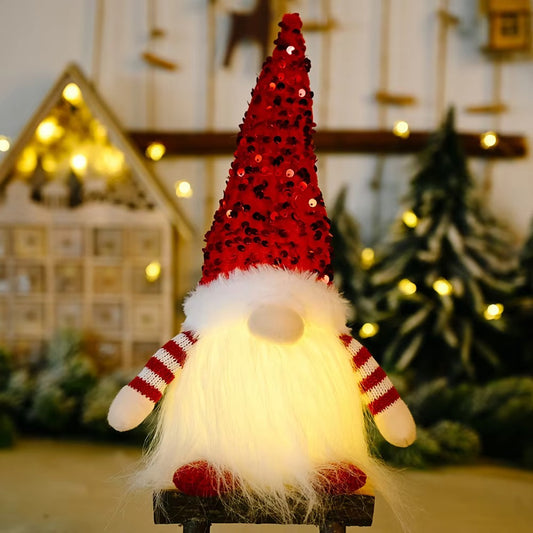 A faceless Christmas gnome doll with a red sequin hat, glowing white beard, and red-and-white striped sleeves sitting on a wooden stool in a festive background.