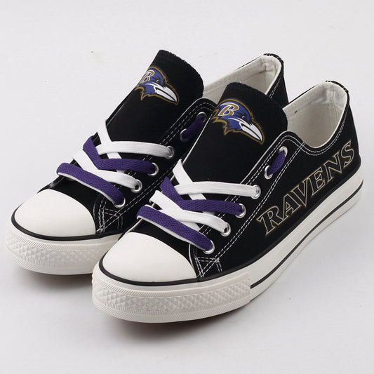 Close-up of black Baltimore Ravens low-top canvas sneakers featuring the Ravens logo and purple laces on a clean white background. Essential NFL supporter shoes.
