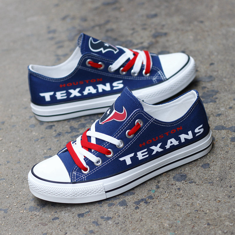 One large and one small navy blue Houston Texans canvas sneaker leaning against a stone wall outdoors. Shows the red laces and the iconic bull logo.