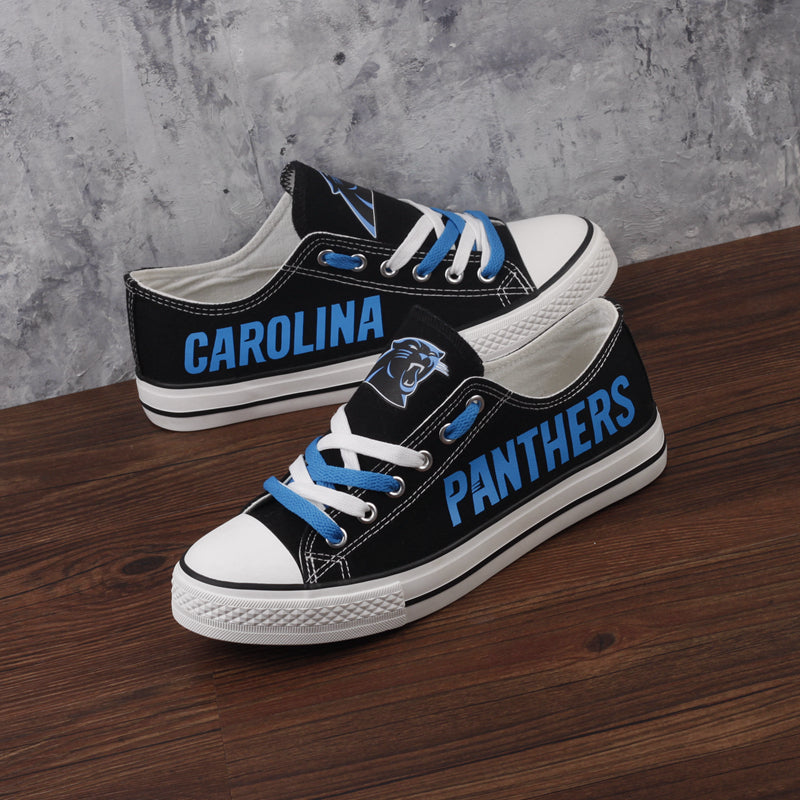 Black Carolina Panthers canvas sneakers on a wooden surface, showcasing the blue 'CAROLINA' and 'PANTHERS' text and the panther logo.