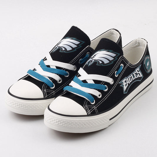 Pair of black Philadelphia Eagles canvas low-top shoes with teal/blue and white laces. Features the Eagles logo and bold 'EAGLES' text. Perfect NFL fan footwear.