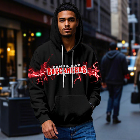 Male model wearing a black Tampa Bay Buccaneers hoodie with red lightning graphics on the sleeves and team logo on the chest, standing confidently in an urban street setting.
