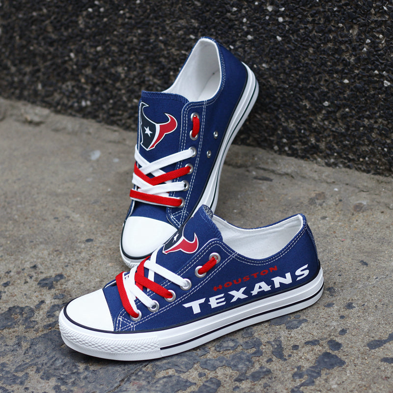 Pair of navy blue Houston Texans canvas low-top shoes on a gray concrete surface. Features the vibrant white 'TEXANS' lettering and the classic team emblem.