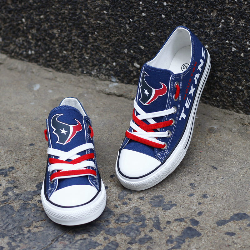 Navy blue Houston Texans canvas sneakers resting against a dark textured wall outdoors. Highlights the white 'TEXANS' lettering and the bull logo for an urban fan vibe.